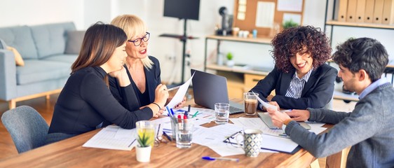Group of business workers smiling happy and confident. Working together with smile on face  using laptop and speaking at the office