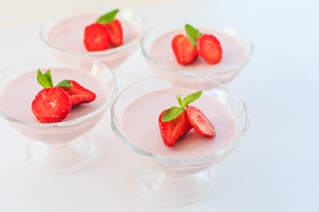 delicate strawberry ice cream with slices of strawberries with cream in a glass bowl on a light background, for advertising confectioners or sweets