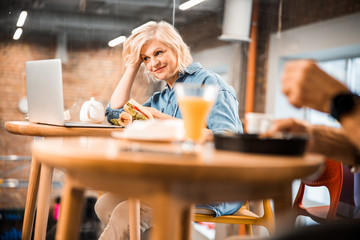 Smiling adult woman having snack in cafe