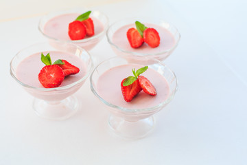 delicate strawberry ice cream with slices of strawberries with cream in a glass bowl on a light background, for advertising confectioners or sweets