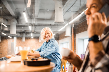 Happy adult woman using laptop while having lunch