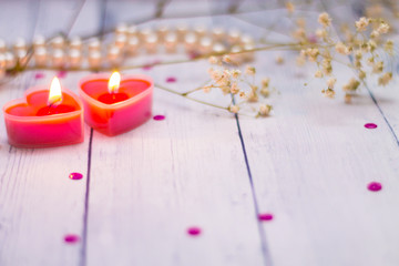 two red burning candles hearts pearls flowers close up