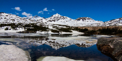 Fototapeta na wymiar Snow Capped Mountains and Ice Reflection in Pond Yukon CA
