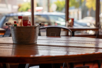 Steel bucket of condiments and sauces on restaurant table
