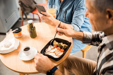 Adult man eating food from box in cafe