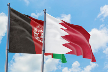 Bahrain and Afghanistan flags waving in the wind against white cloudy blue sky together. Diplomacy concept, international relations.