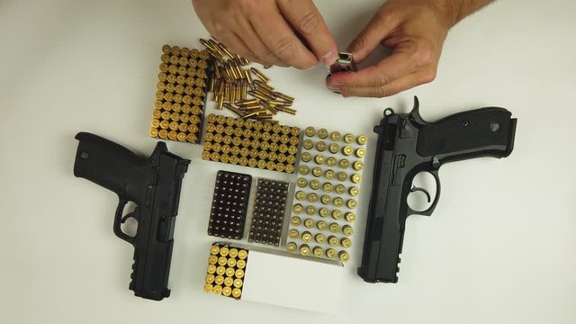 A man loading handgun magazine with  22lr ammunition on the white background.