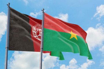 Burkina Faso and Afghanistan flags waving in the wind against white cloudy blue sky together. Diplomacy concept, international relations.