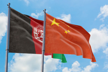 China and Afghanistan flags waving in the wind against white cloudy blue sky together. Diplomacy concept, international relations.