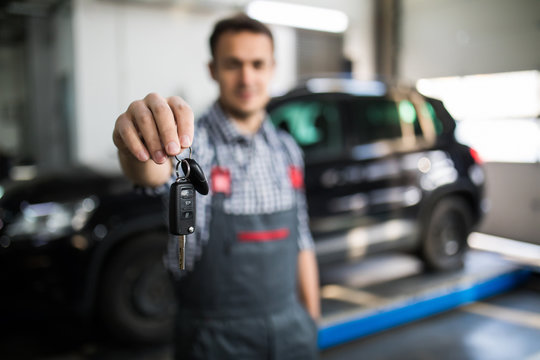 Mechanic handling keys of a car at the service garage - Powered by Adobe