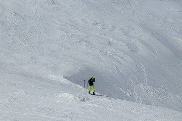 Tourist in alps photographs the valley below him. Swiss Alps and only one freeride man. Young boy downhill slope and stop before a edge and take a phone a do some photos. Winter paradise