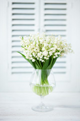 Bouquet of fresh white lilies of the valley in a glass goblet