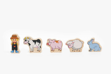 wooden figure of a boy, cow, pig, sheep and rabbit on a white background