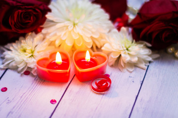 two red burning burning candles hearts flowers bow close up pearls