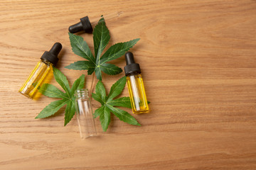 CBD oil among cannabis leaves on a wooden background