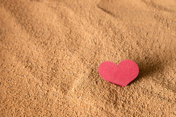 The burgundy heart is stuck in the sandy surface.