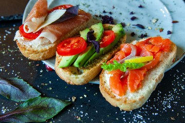 Appetizing bruschetta. Traditional Italian bruschetta. Open sandwich with salmon and vegetables. Delicious healthy food. European cuisine. 