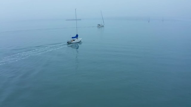 Fishing and sail boats set out for the day in the early morning fog inversion.