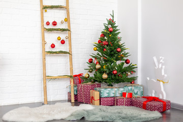 Artificial Christmas tree with gifts. Cozy goal in the apartment. Winter.