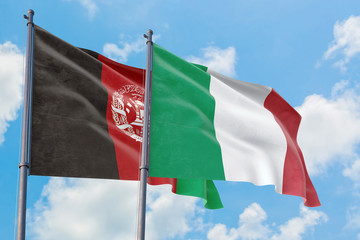 Italy and Afghanistan flags waving in the wind against white cloudy blue sky together. Diplomacy concept, international relations.