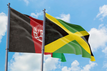 Jamaica and Afghanistan flags waving in the wind against white cloudy blue sky together. Diplomacy concept, international relations.