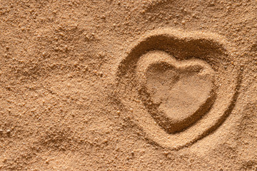 A heart is drawn on the surface of the sand.