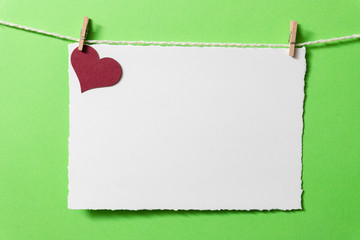 Postcard template with burgundy heart and tiny clothespins on a green background.
