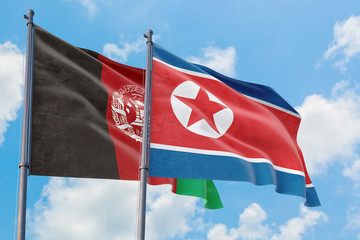 North Korea and Afghanistan flags waving in the wind against white cloudy blue sky together. Diplomacy concept, international relations.