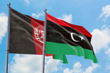 Libya and Afghanistan flags waving in the wind against white cloudy blue sky together. Diplomacy concept, international relations.