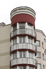 multi-storey modern white stucco building with round towers and balconies.