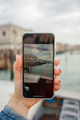 Hands taking picture of Venice, Italy with smartphone camera. Travel concept.