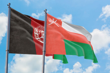 Oman and Afghanistan flags waving in the wind against white cloudy blue sky together. Diplomacy concept, international relations.