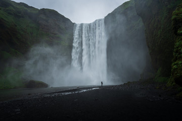 Majestic skogafoss in Iceland, cloudy day with one person in front