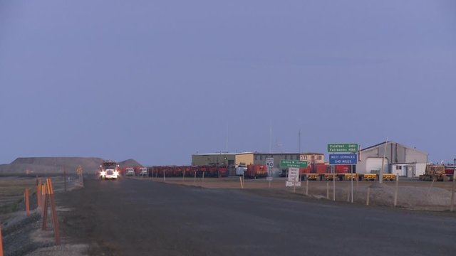 Dalton Highway and Deadhorse, Alaska. Petrol truck passes by. Buildings of dead horse with oil drilling equipment in the back.
Beautiful light of midsummer night.
