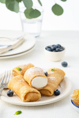 Crepes, thin pancakes with cream cheese and fresh blueberries.
