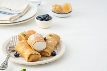 Crepes, thin pancakes with cream cheese and fresh blueberries.