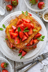 French toasts, French toasts made of sliced brioche with fresh strawberries and honey on a plate,...