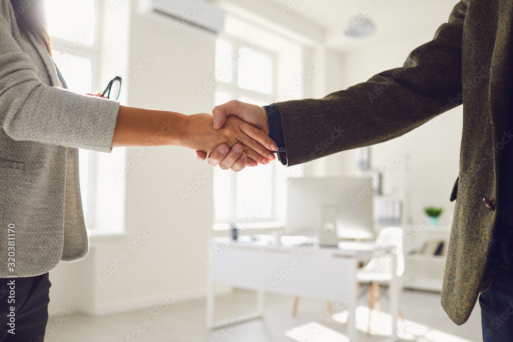 Wall mural handshake of businessmen. female and male hand makes a handshake in the office.