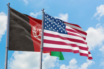 United States and Afghanistan flags waving in the wind against white cloudy blue sky together. Diplomacy concept, international relations.
