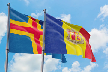 Andorra and Aland Islands flags waving in the wind against white cloudy blue sky together. Diplomacy concept, international relations.