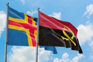 Angola and Aland Islands flags waving in the wind against white cloudy blue sky together. Diplomacy concept, international relations.