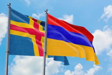 Armenia and Aland Islands flags waving in the wind against white cloudy blue sky together. Diplomacy concept, international relations.