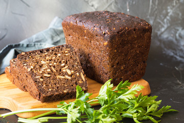Bread on flour leaven with pumpkin seeds, on a cutting board and slices of bread on gray background. The concept of healthy eating. Homemade cake.