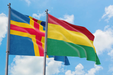 Bolivia and Aland Islands flags waving in the wind against white cloudy blue sky together. Diplomacy concept, international relations.