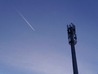 Cell tower and trail from an airplane in the blue sky