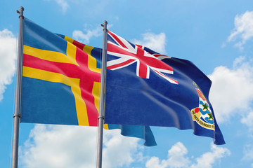 Cayman Islands and Aland Islands flags waving in the wind against white cloudy blue sky together. Diplomacy concept, international relations.