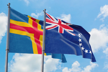 Cook Islands and Aland Islands flags waving in the wind against white cloudy blue sky together. Diplomacy concept, international relations.