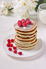 Healthy breakfast: stack of classic american pancakes with berries (raspberries) and milk. White background