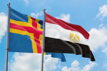 Egypt and Aland Islands flags waving in the wind against white cloudy blue sky together. Diplomacy concept, international relations.