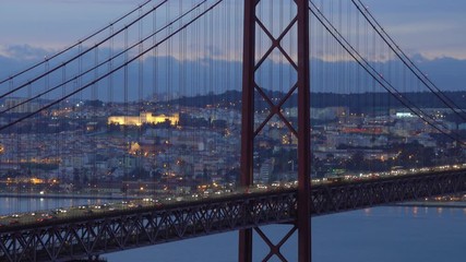 The Bridge of 25th April with car traffic and panoramic view of the city on the background after sunset, Lisbon, Portugal, 4k